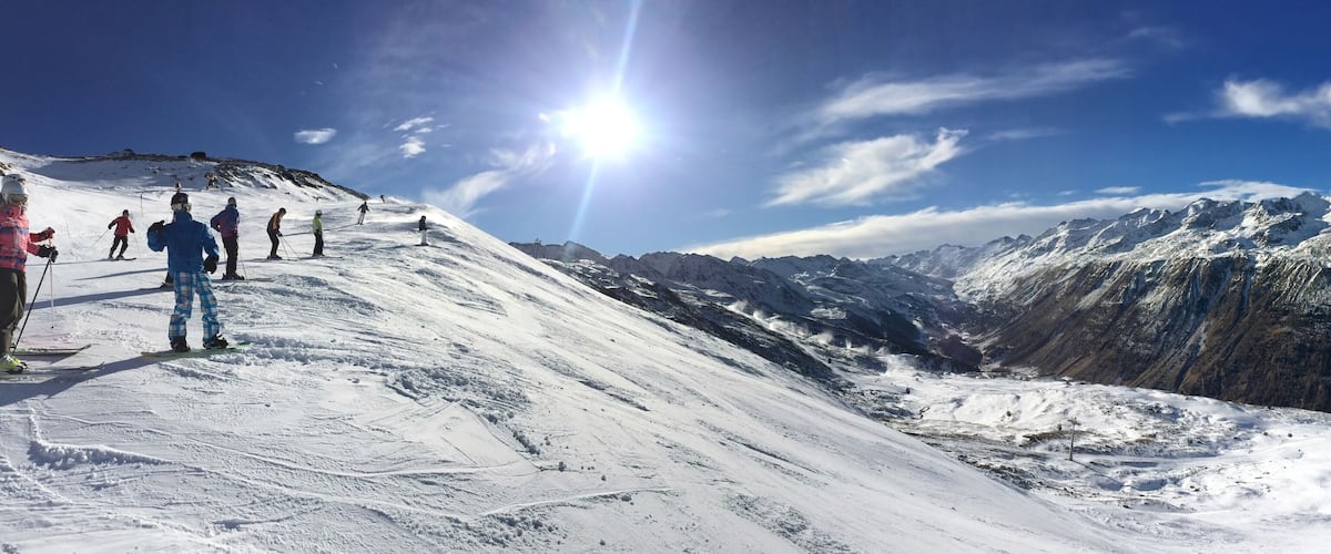 A snowy mountain slope with skiers and a clear blue sky.