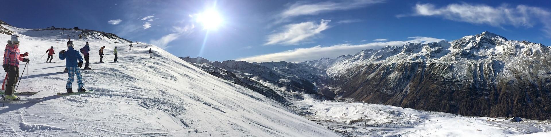 A snowy mountain slope with skiers and a clear blue sky.