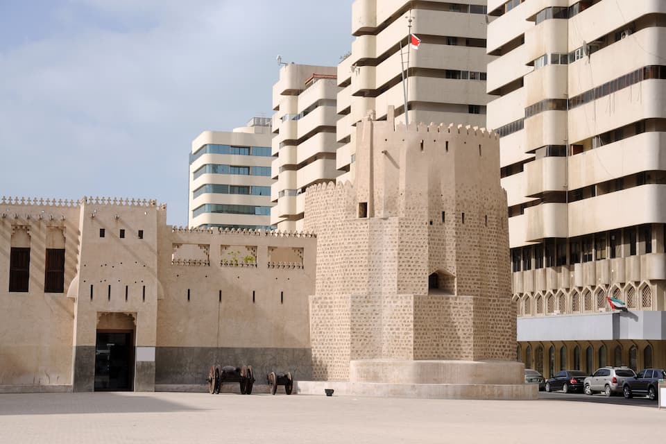 Una estructura que recuerda a un castillo, con una bandera, rodeada de edificios modernos.