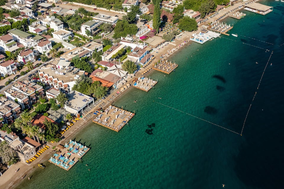 An aerial view of a coastal town with a marina, beach, and residential buildings.