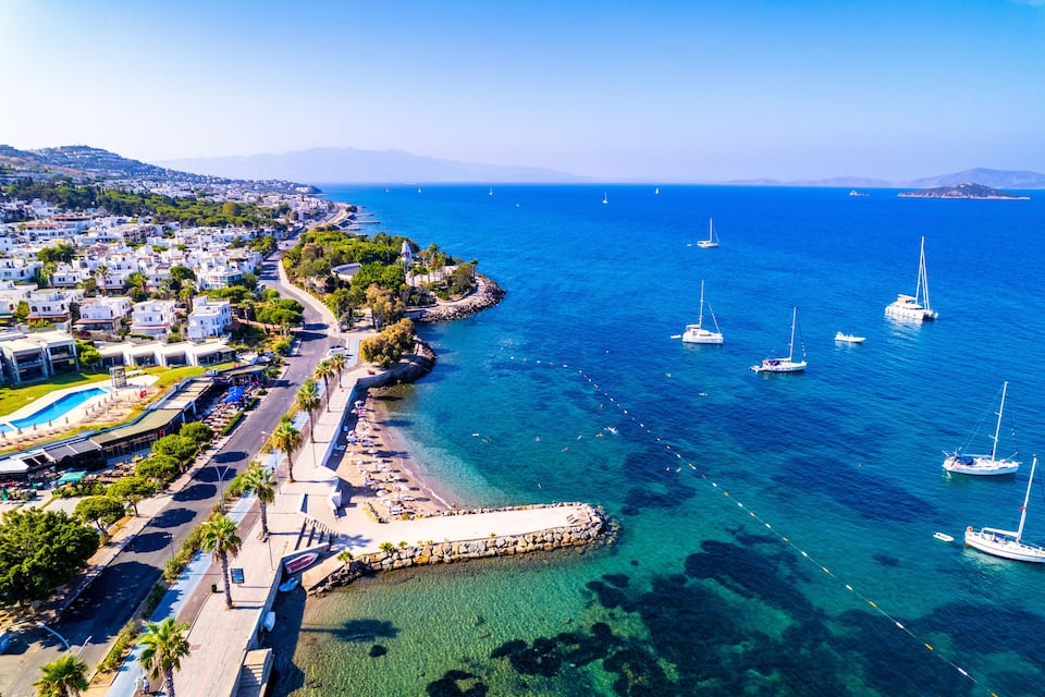 A coastal town with a clear blue sea, boats, and a beach.