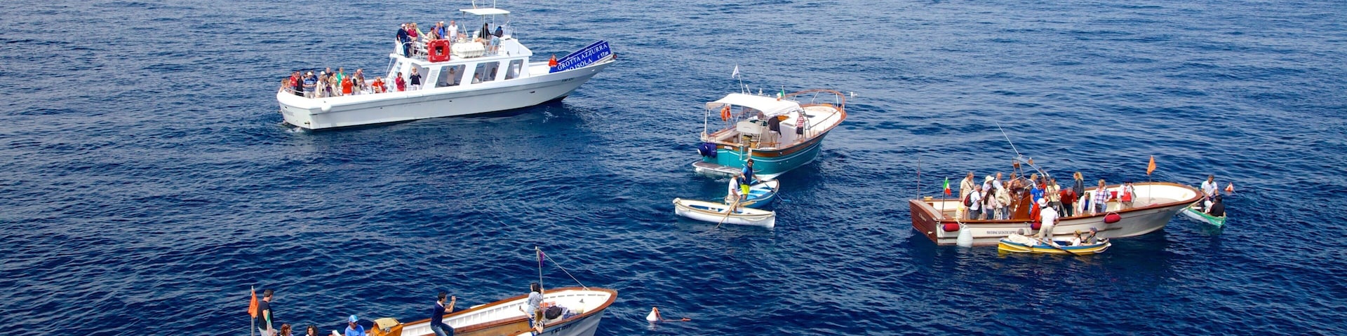 Blue Grotto featuring general coastal views and boating as well as a large group of people