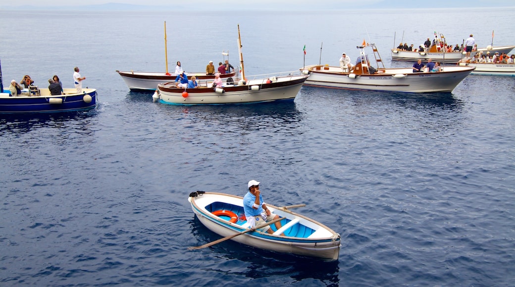 Blue Grotto showing boating and a bay or harbor as well as a large group of people