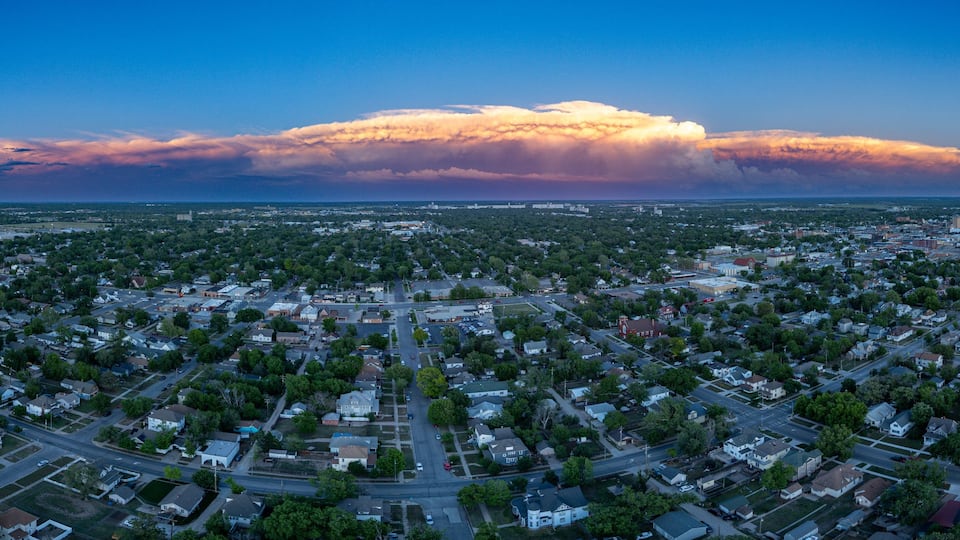 A cityscape with a large cloud formation in the sky.