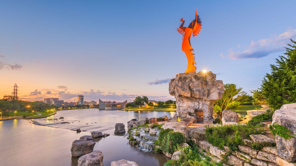 A river with a waterfall, a rock formation, and a statue.