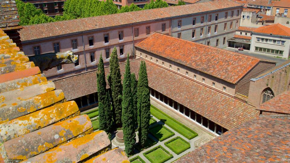 A courtyard with a tiled roof, tall cypress trees, and a building with multiple windows.