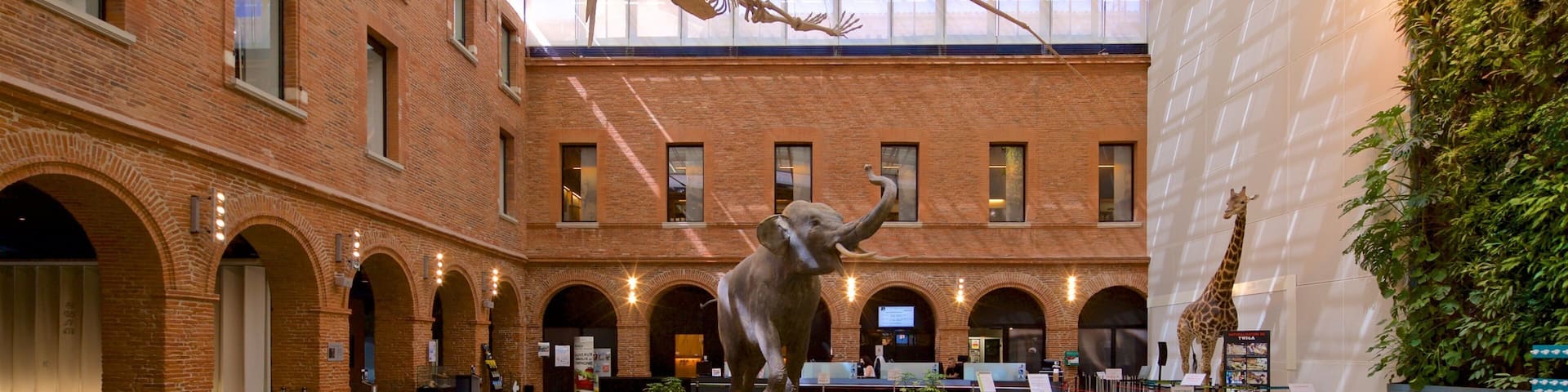 A spacious interior with a high ceiling, brick walls, and a central sculpture of an elephant.