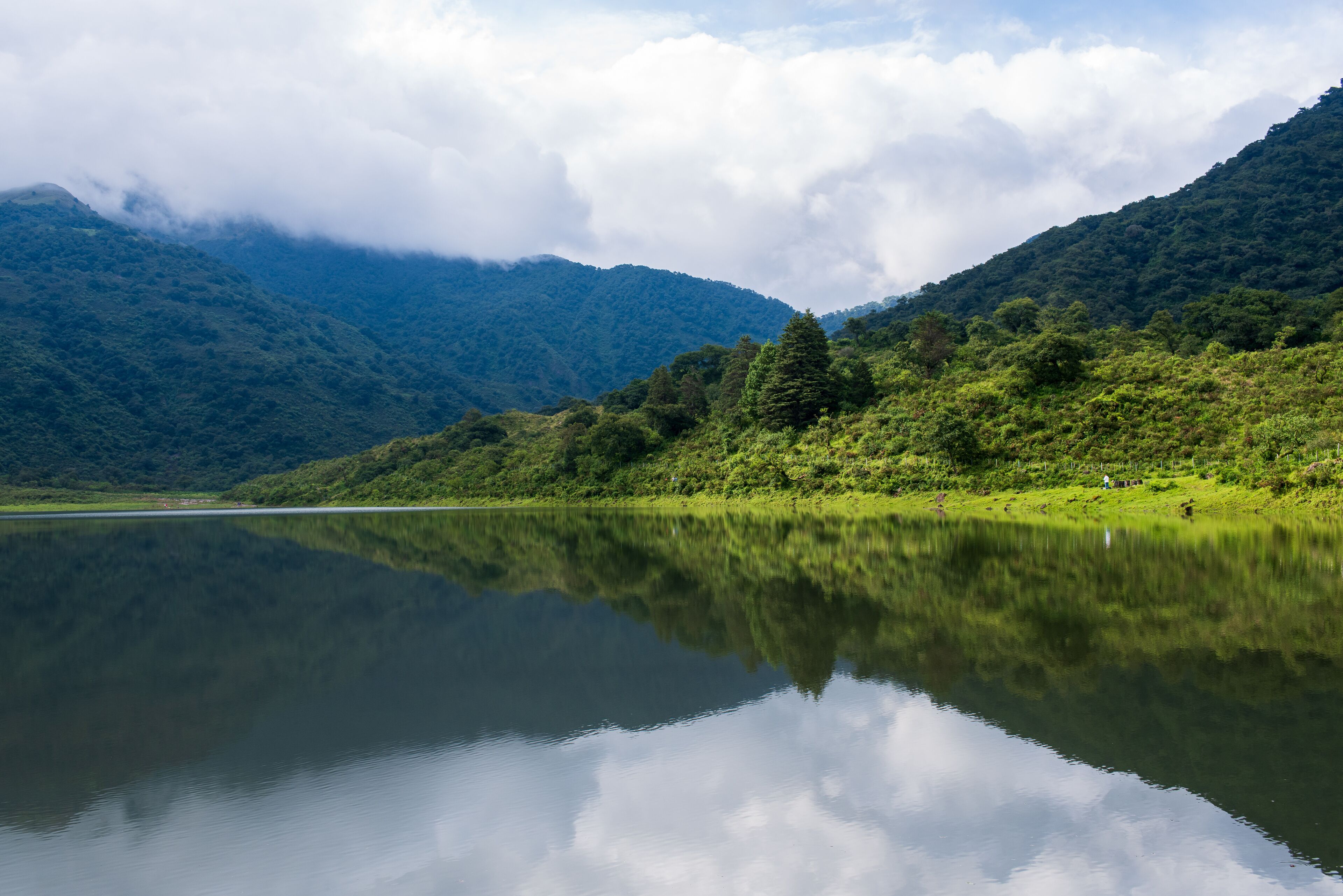 A calm lake reflecting mountains and clouds.