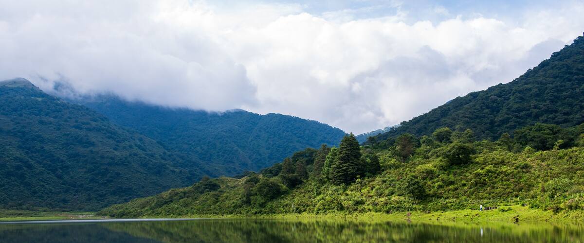 A calm lake reflecting mountains and clouds.
