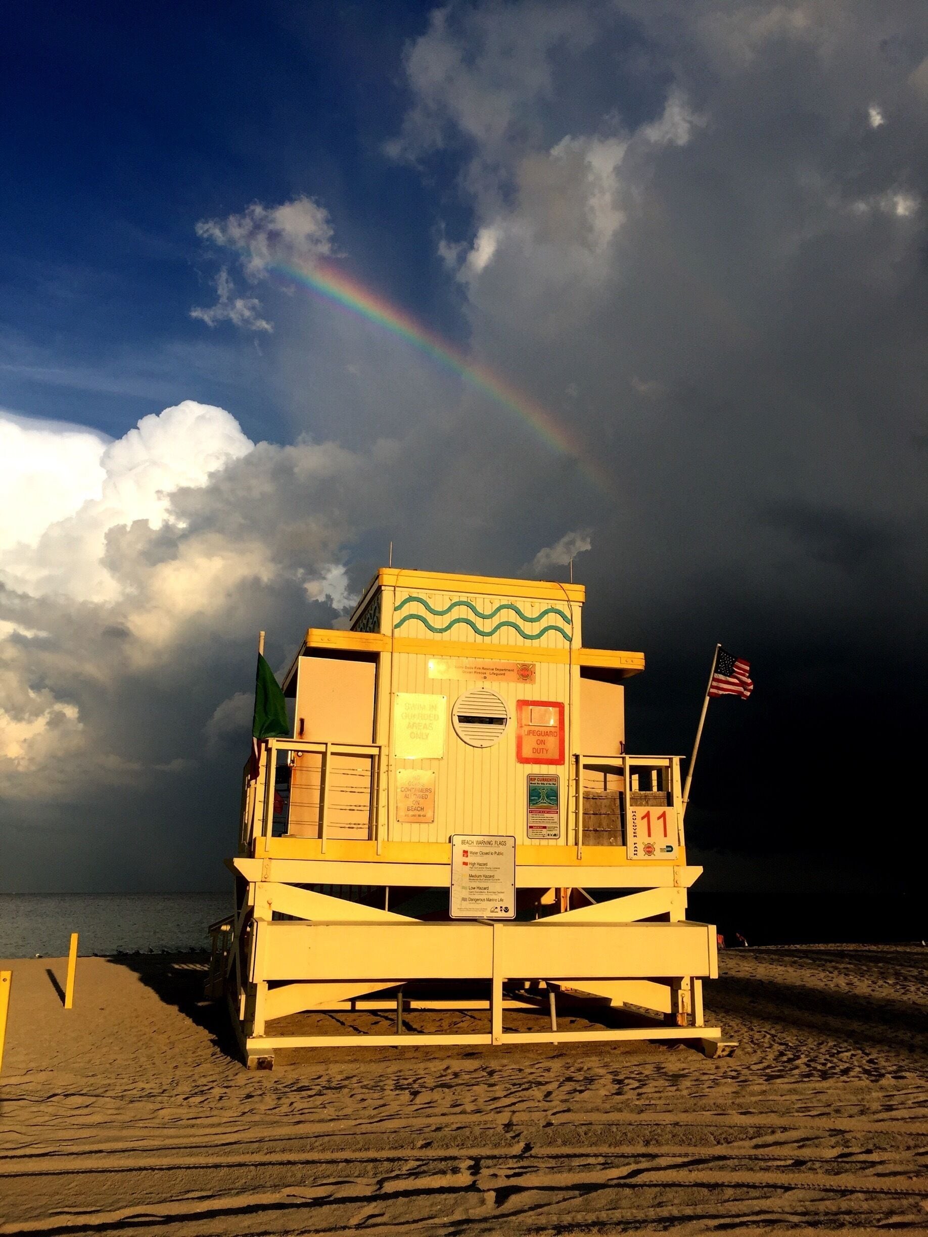 The spirit of Miami through the lifeguard post shining in the setting sun against the backdrop of the ocean and a rainbow 