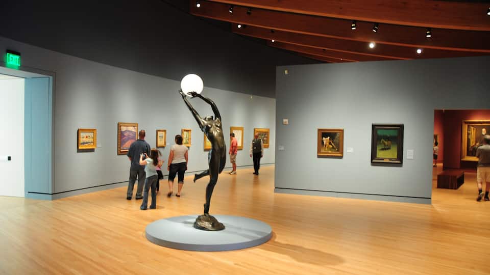 An art gallery with wooden floors and paintings on the walls.
