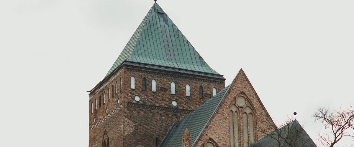 A church with a steeply pitched roof and a cross on top.