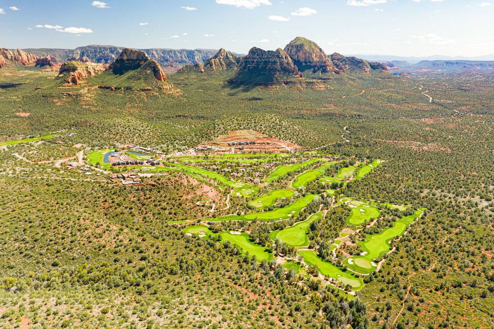 An aerial view of a golf course surrounded by rugged mountains and sparse vegetation.