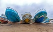 Low and wide angle view of several boats on the beach sand, on logs, on an overcast morning. Puerto Cayo, Manabi, Ecuador