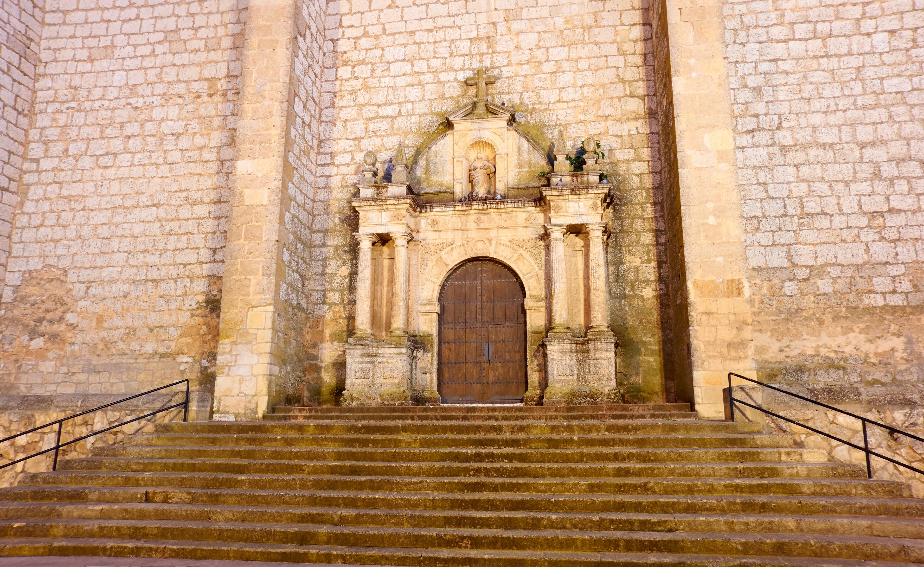 A stone church with a large wooden door and steps leading up to it.