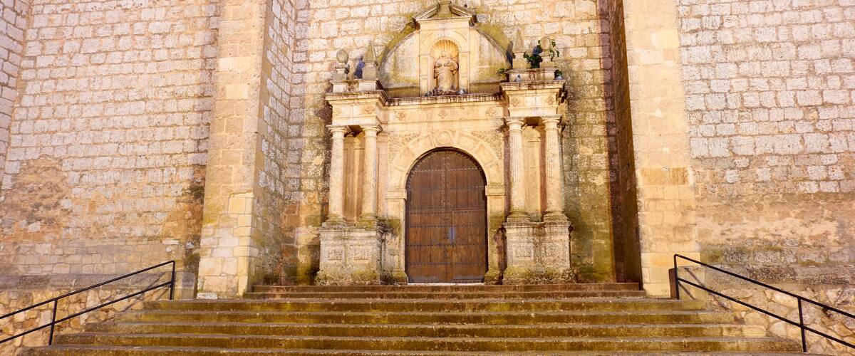 A stone church with a large wooden door and steps leading up to it.