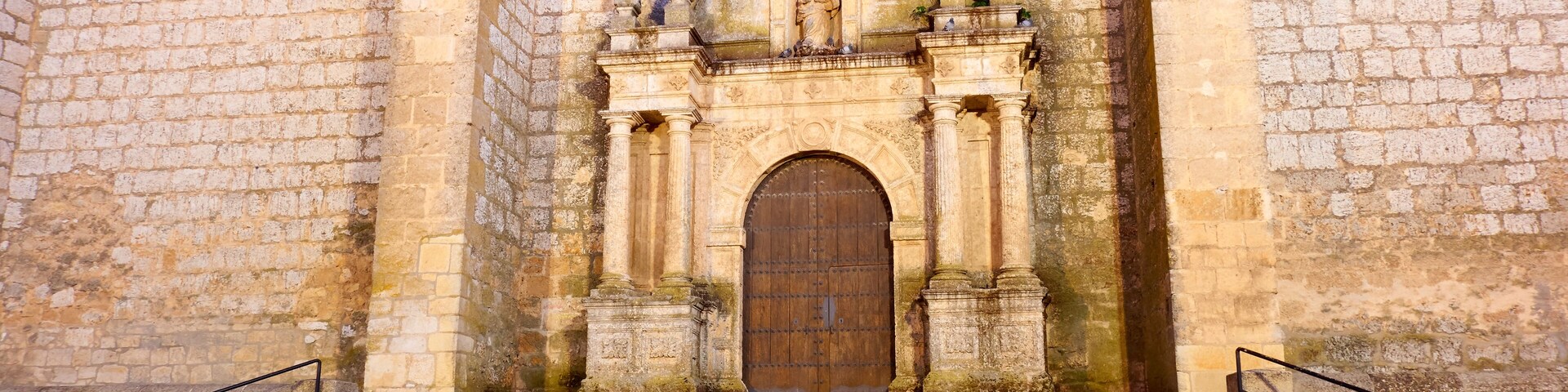 A stone church with a large wooden door and steps leading up to it.