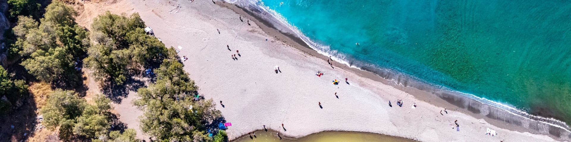 A coastal landscape with a sandy beach, clear turquoise waters, and a small river or lagoon.