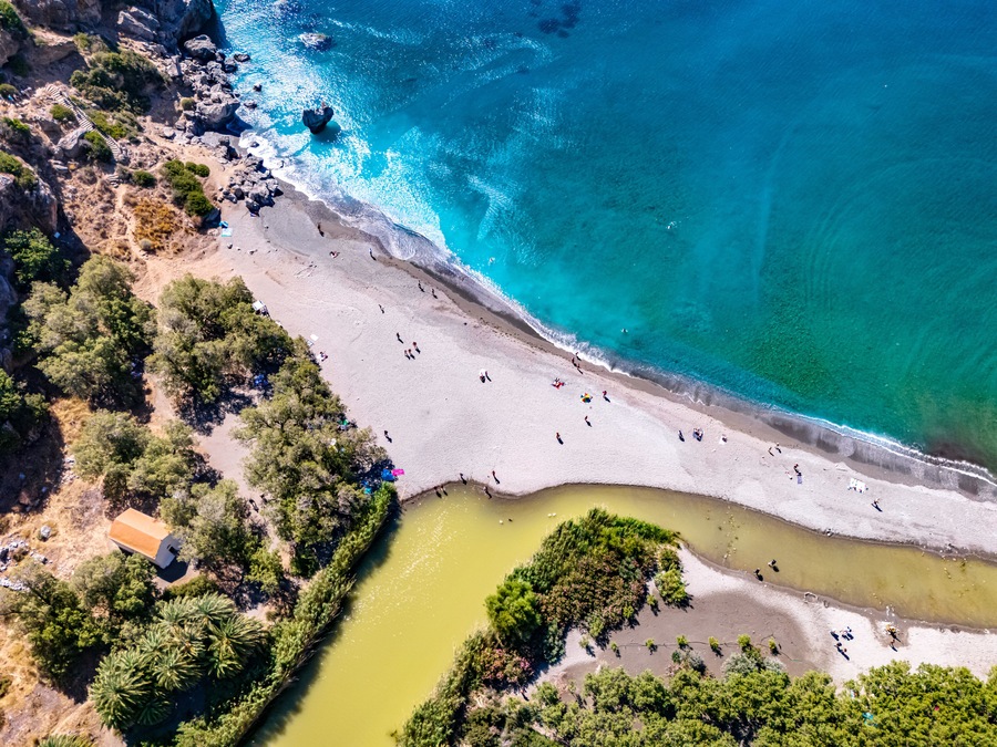 Un paysage côtier avec une plage de sable, des eaux turquoise et limpides, et une petite rivière ou un lagon.