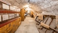 A tunnel with stone walls, wooden barrels, and historical exhibits.