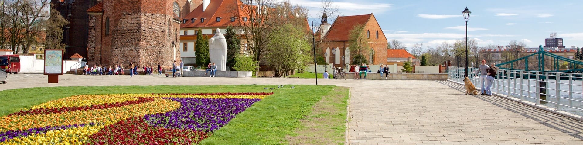 A historic church with a tall spire and a colorful flower garden in front.