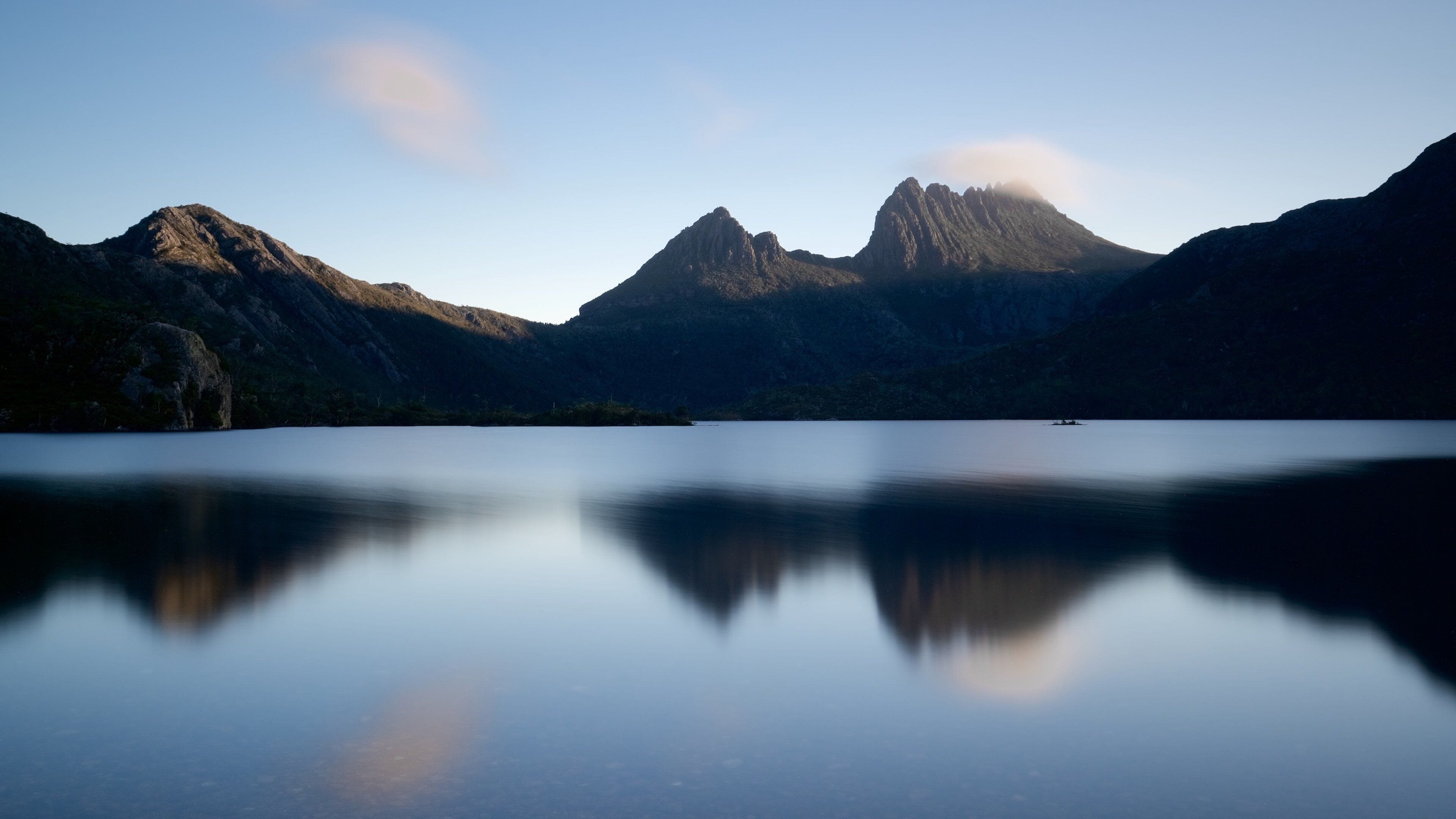 A calm lake with mountains in the background.