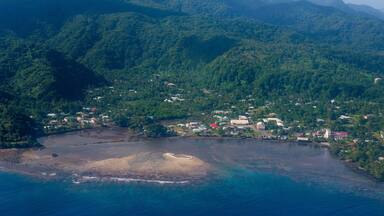 A coastal town nestled between lush green hills and a clear blue sea.