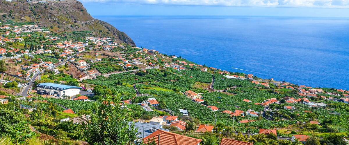 A coastal town with houses, a large building, and a cliff overlooking the ocean.