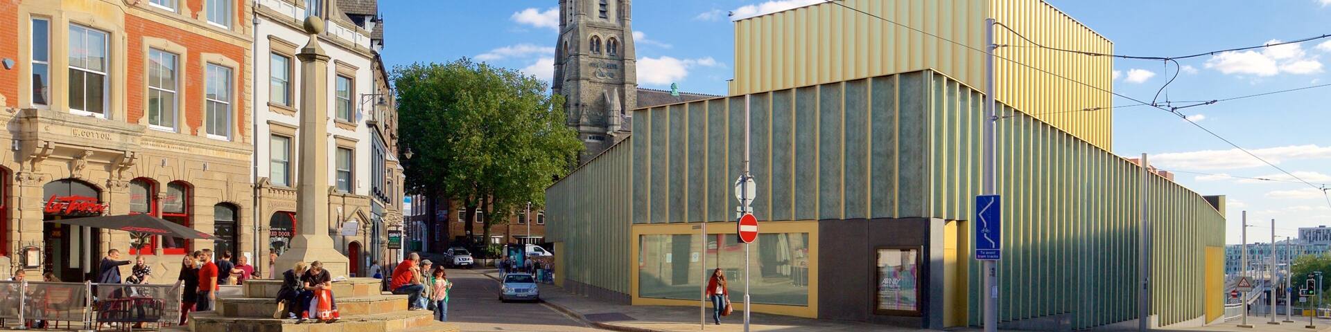 A street with historic buildings, a modern glass building, and a church spire.