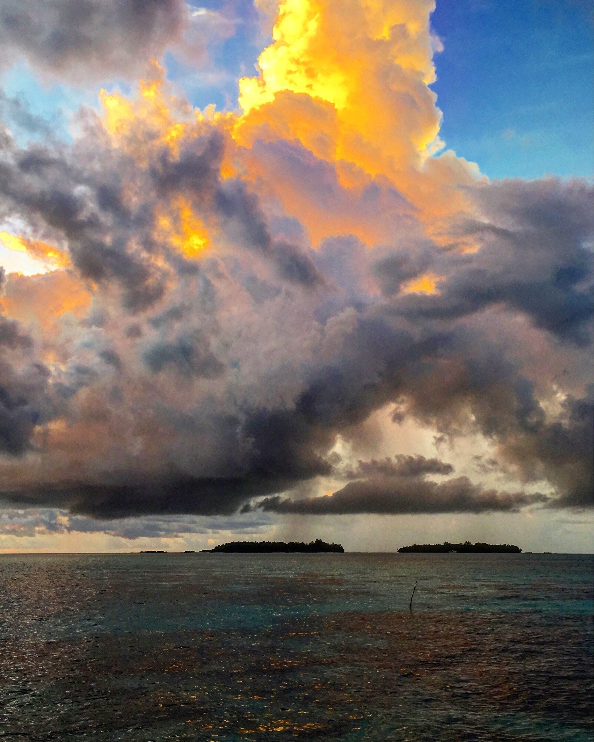 Um pôr do sol sobre a água, com uma ilha ao longe.