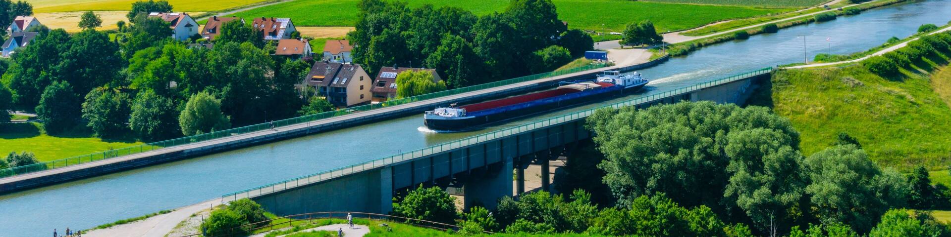 A river with a bridge, green fields, and a boat.