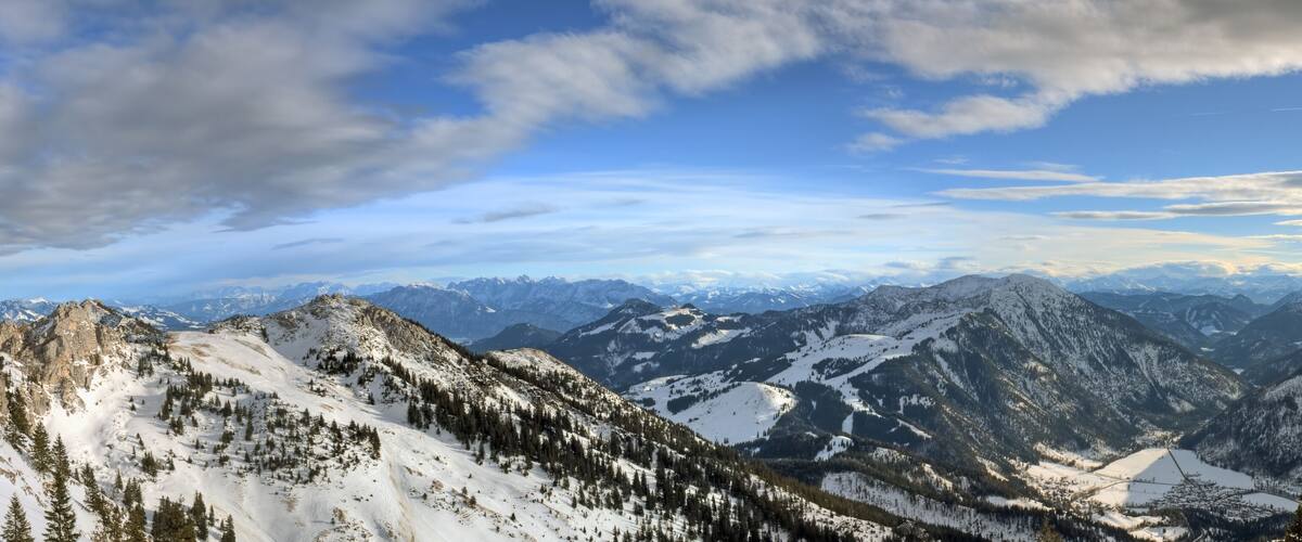 A snow-covered mountain range with a church on a hill and a prominent rocky peak.
