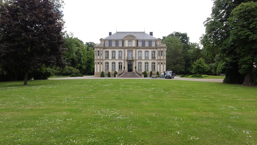 A large, historic building with a symmetrical facade, surrounded by a well-maintained lawn and trees.
