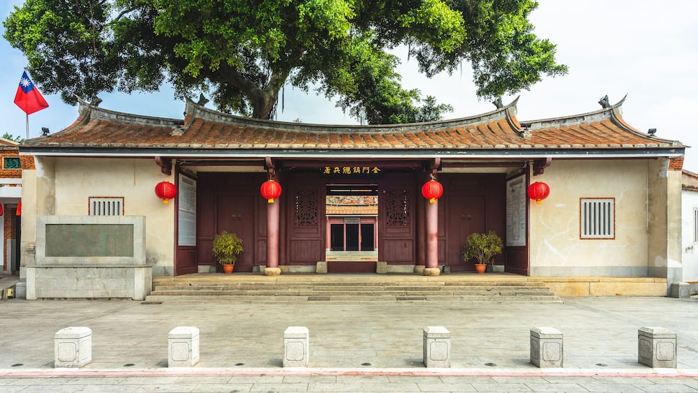 A traditional building with a tiled roof, red lanterns, and a flag.