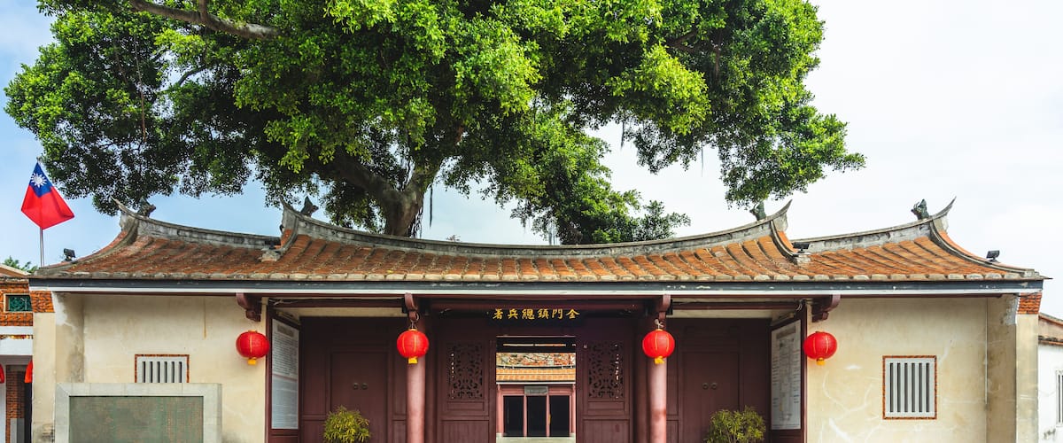 A traditional building with a tiled roof, red lanterns, and a flag.