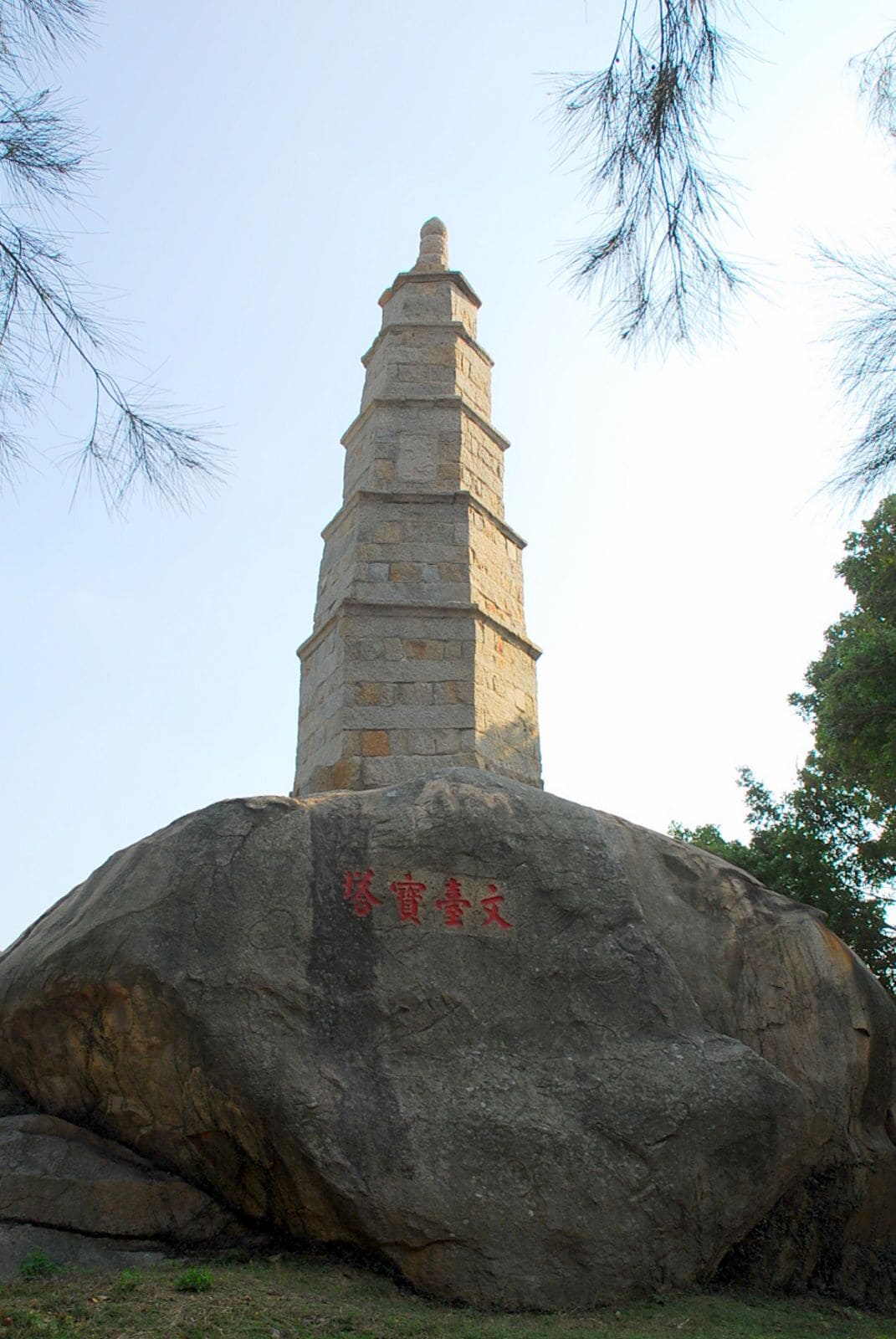 A stone pagoda on a large rock with Chinese characters.