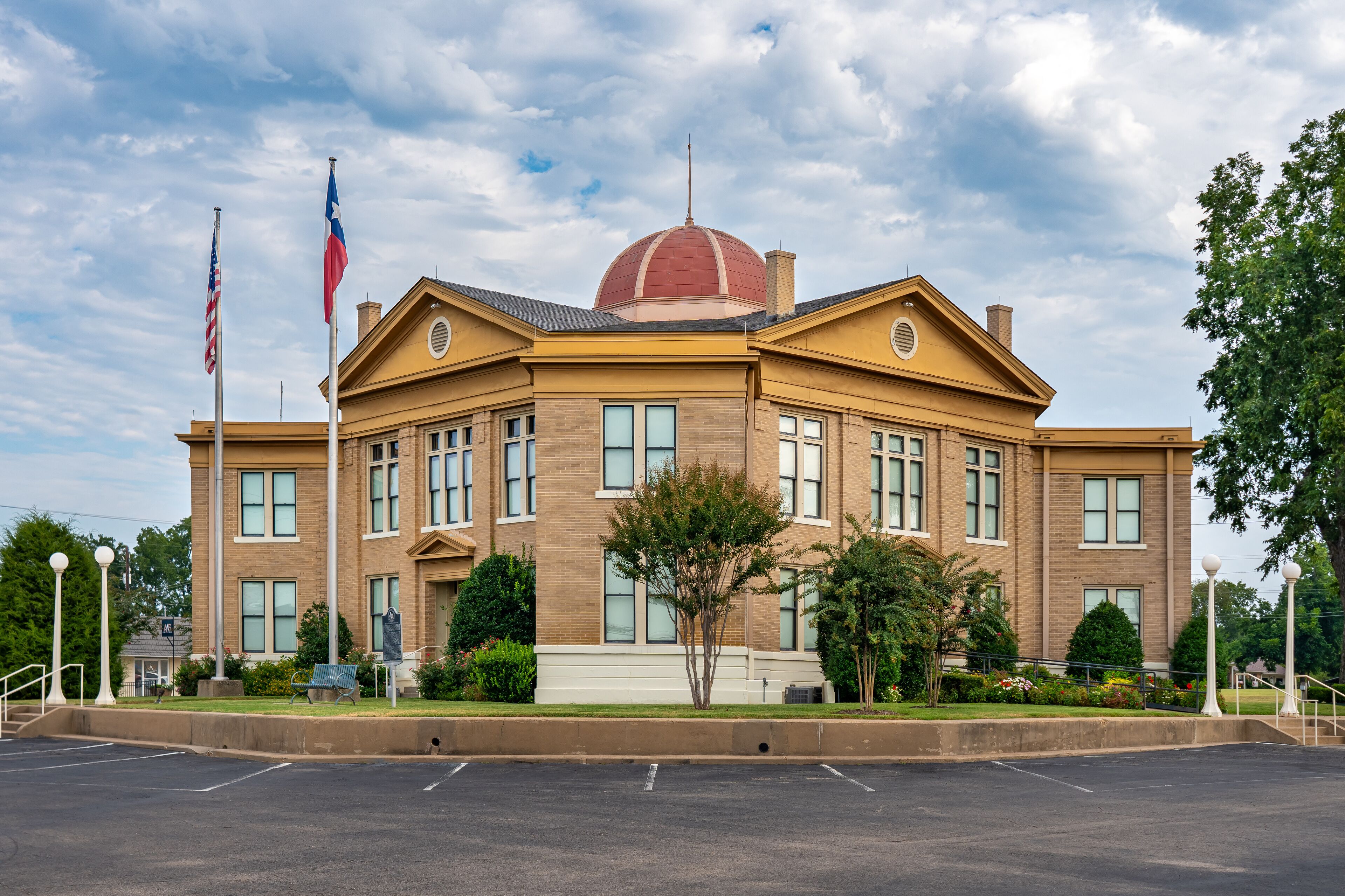 A large brick building with a red dome and two flags.
