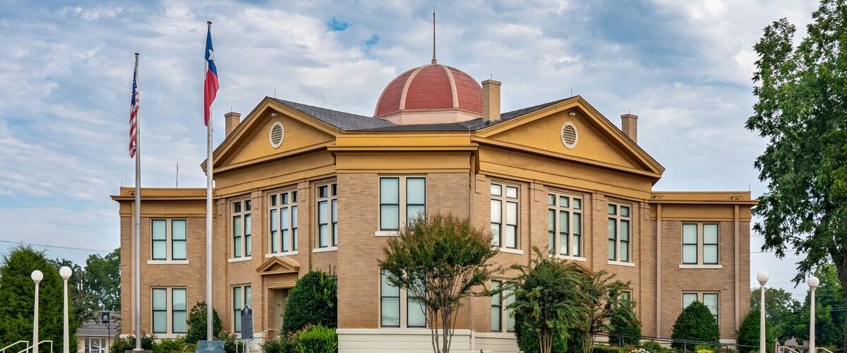 A large brick building with a red dome and two flags.