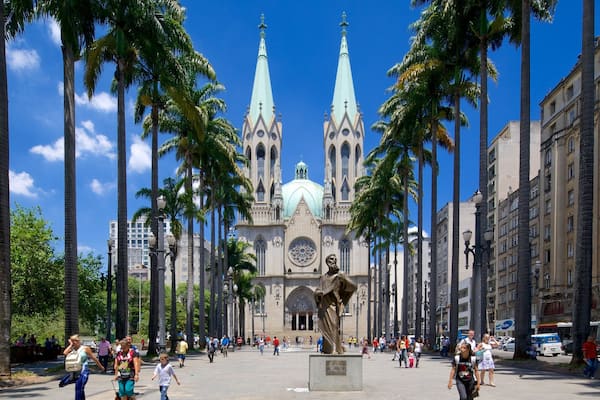 Une cathédrale dotée de deux flèches jumelles et d’un grand dôme, entourée de palmiers et animée par la présence de passants.