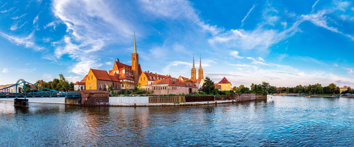 A historic town with a prominent church and twin spires, a bridge, and a calm river.