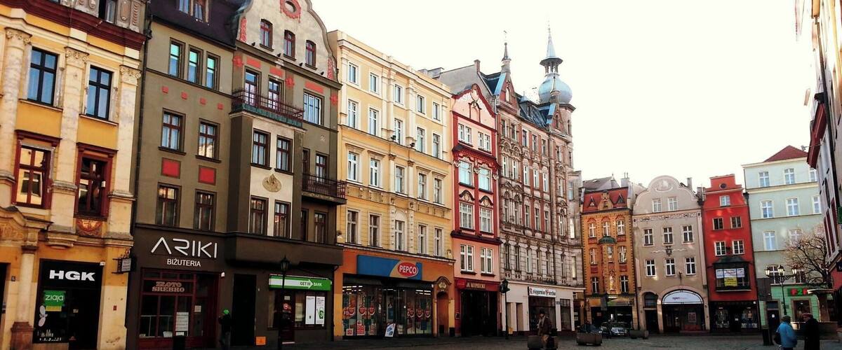 A cobblestone square with historic buildings, including a bank and a restaurant.
