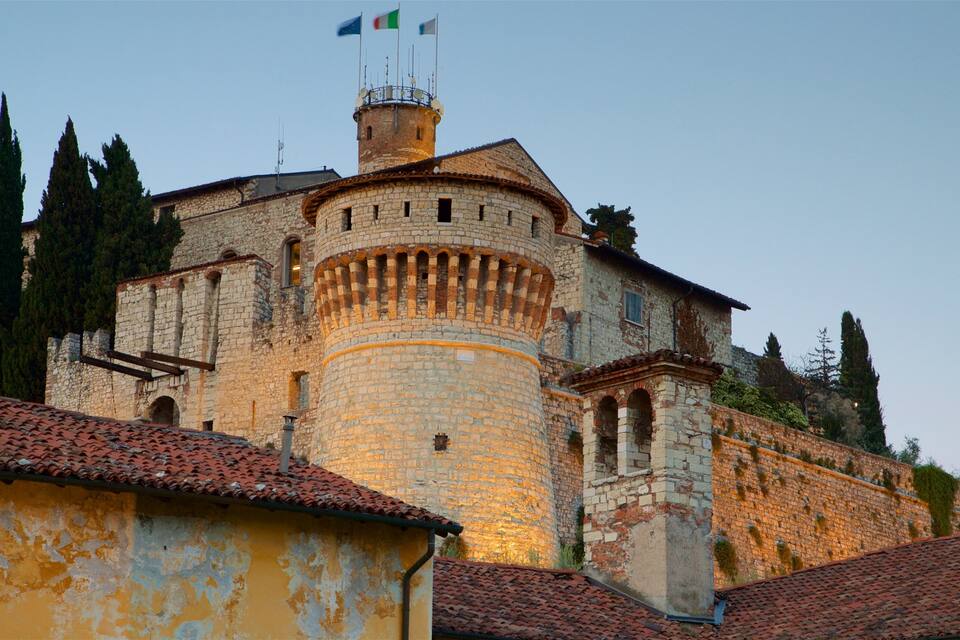 A historic stone tower with a flag on top, surrounded by trees and buildings.