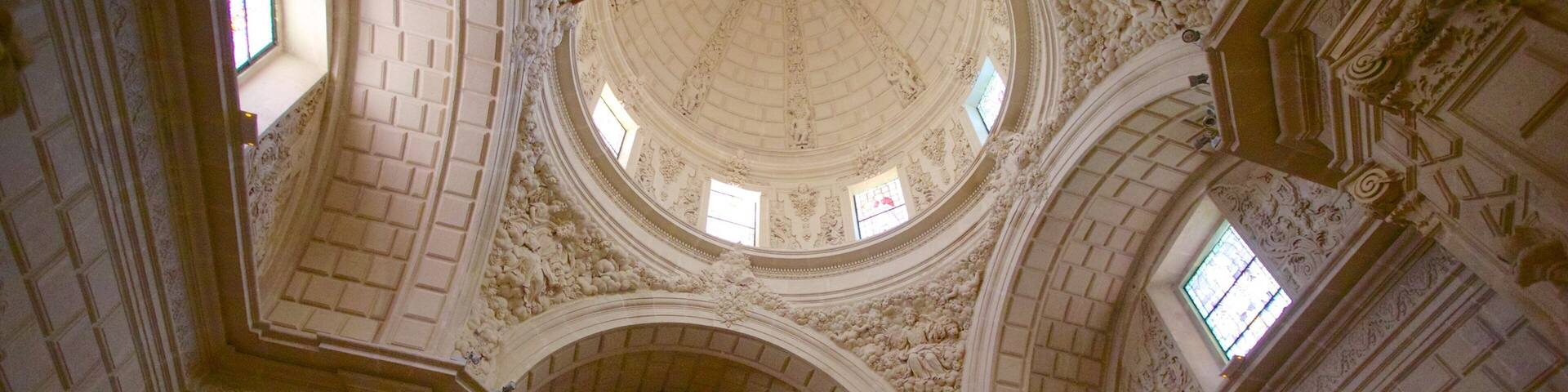 An ornate church interior with a high ceiling, intricate carvings, and a central altar.