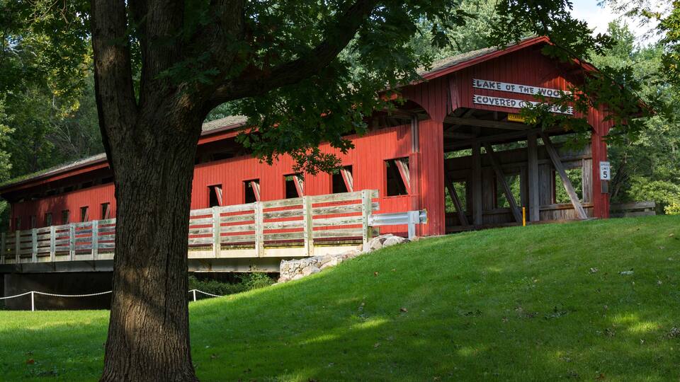 A red covered bridge with a sign that reads "Lake of the Woods Covered Bridge."