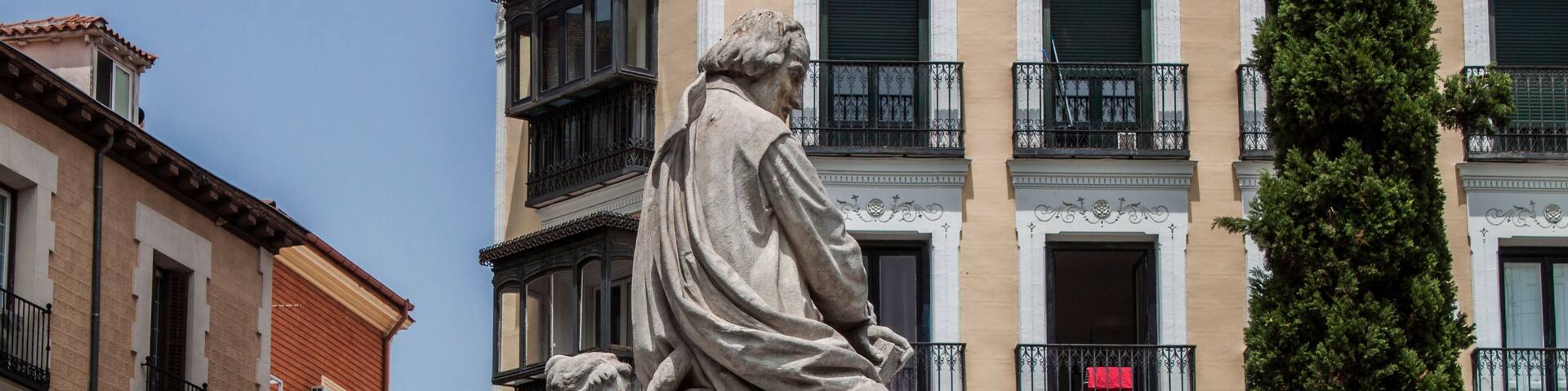 A statue of a man and a child in a courtyard with buildings in the background.