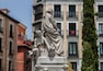 Una estatua de un hombre y un niño en un patio con edificios al fondo.