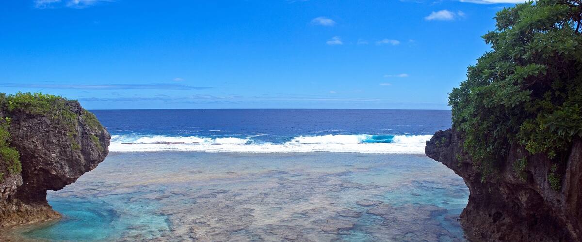 A beach with clear turquoise water, rocky formations, and cliffs.