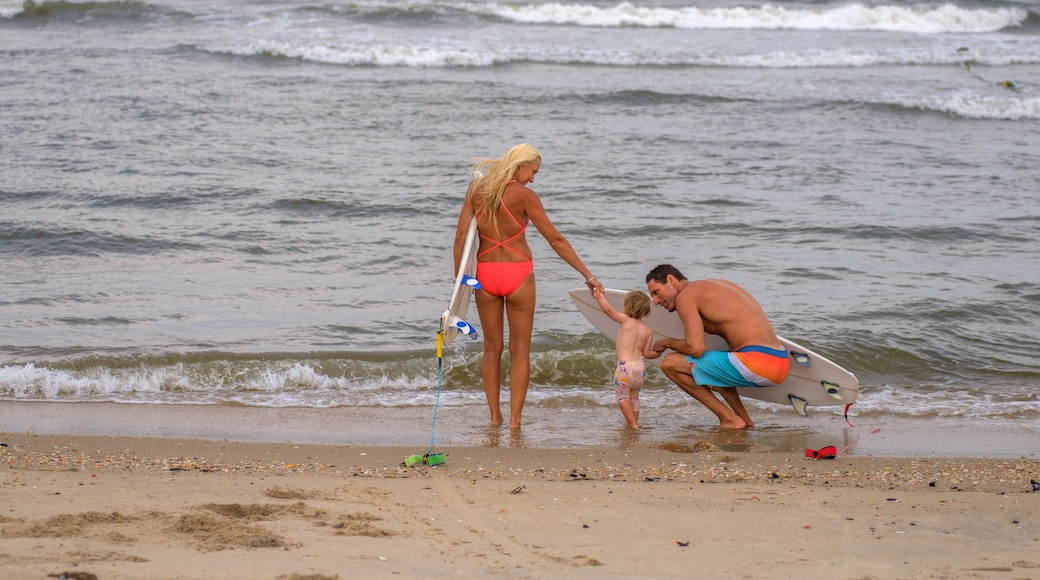 Rear view of surfing couple at water's edge with toddler daughter, Asbury Park, New Jersey, USA