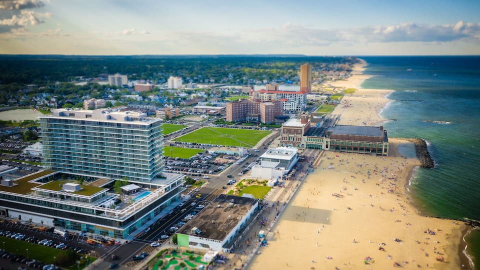 An aerial view of a coastal city with a beach, buildings, and a river.