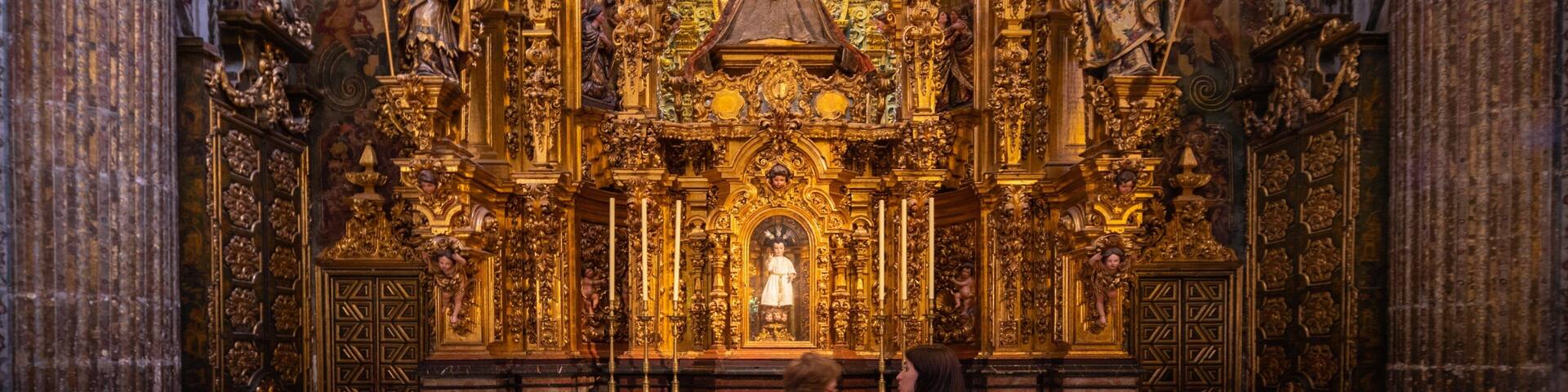 An ornate church interior with golden decorations, a large bell, and religious statues.